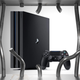 A PlayStation 4 Pro console and its DualShock 4 controller are visible through bent, broken jail bars.